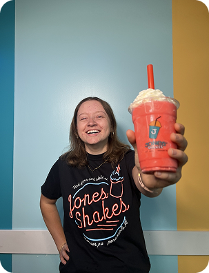 Customer in a Jones Shakes shirt holding a berry milkshake