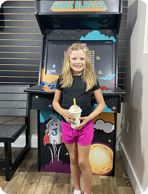 Girl in the Shake Blaster arcade holding a milkshake