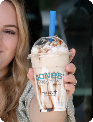 Customer holding a chocolate milkshake in a Jones Shakes cup