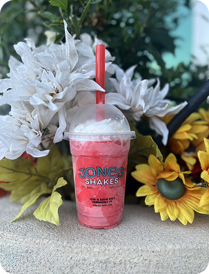 Berry milkshake in a Jones Shakes cup surrounded by sunflowers